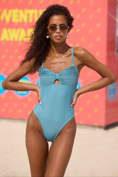 Woman in a blue swimsuit posing in front of a colorful background