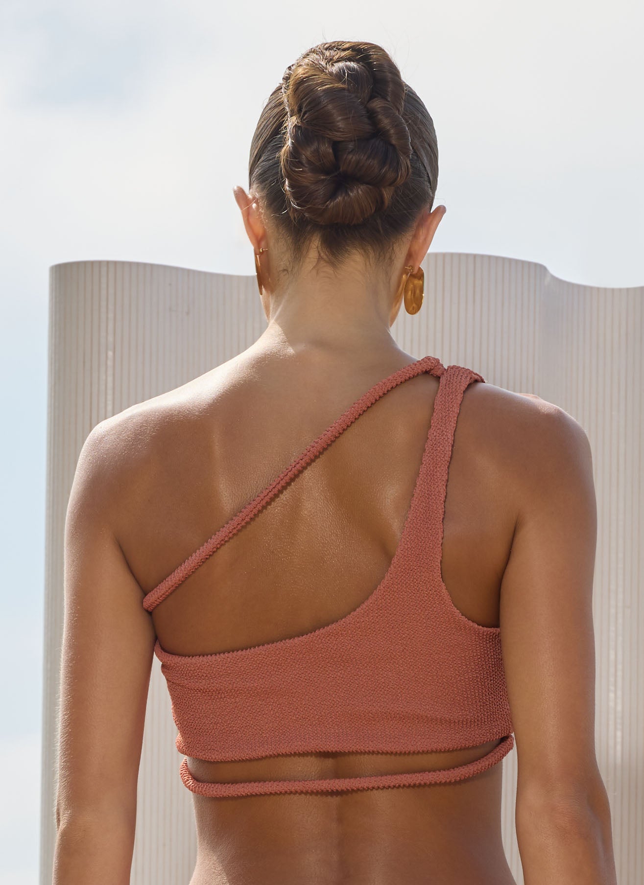 Woman wearing a peach wrap-around design bikini top with a blurred background
